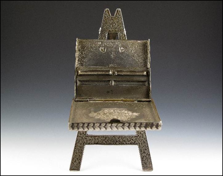 A small metal easel with an open lid
Description automatically generated