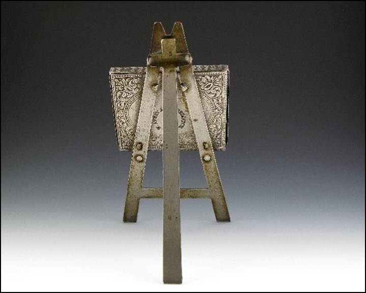 A small metal easel with a small square object
Description automatically generated