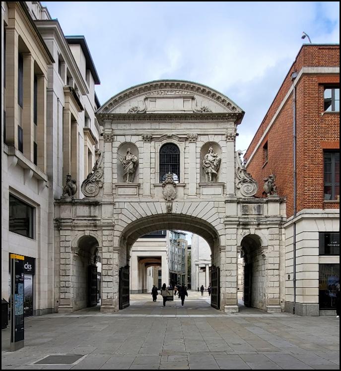 A stone archway with statues on the top
Description automatically generated