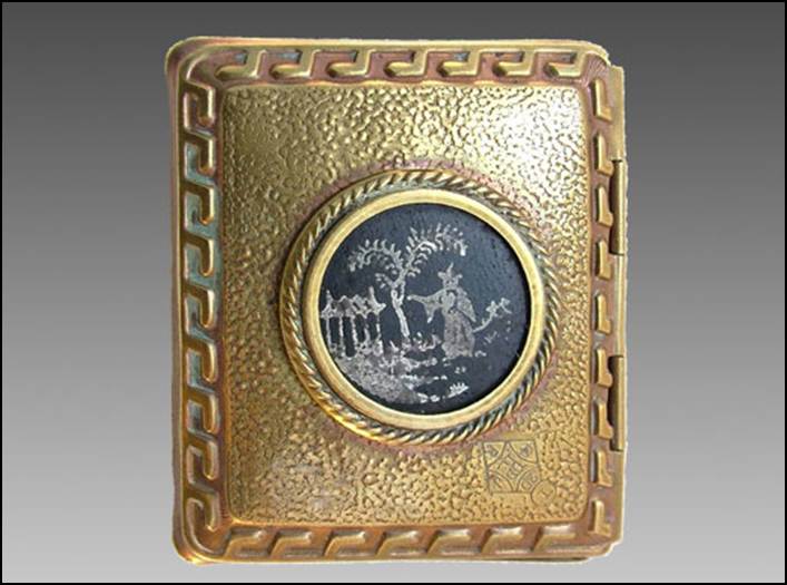 A gold colored rectangular object with a picture on it
Description automatically generated