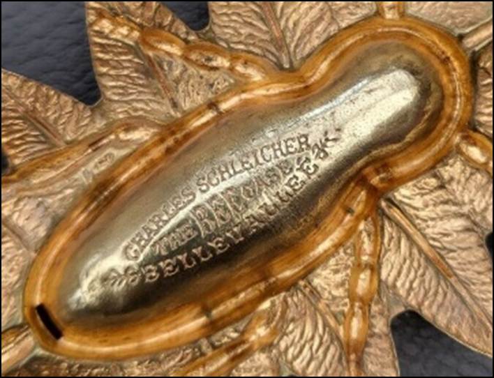 A gold object with a leaf

Description automatically generated